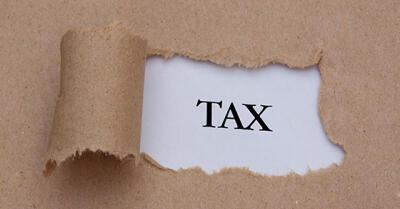 Piece of paper ripped, with opening showing the word "TAX"